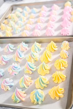 Freshly baked unicorn meringue cookies on a baking sheet with a parchment paper.