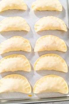 Brushing uncooked turkey empanadas with egg wash.