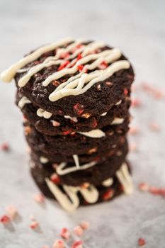 Freshly baked chocolate cookies with peppermint chips with a white chocolate drizzle on top.