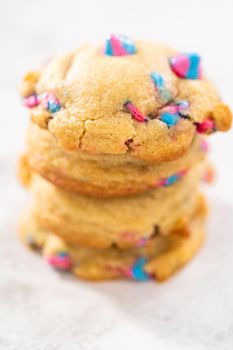 Freshly baked unicorn chocolate chip cookies with rainbow chocolate chips on the counter.