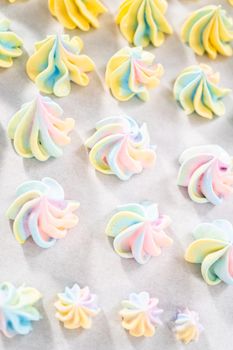 Freshly baked unicorn meringue cookies on a baking sheet with a parchment paper.