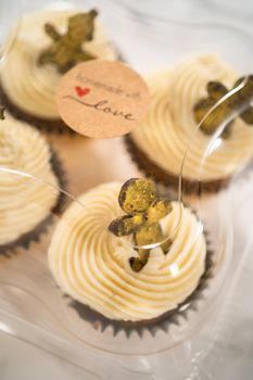 Packaging freshly baked gingerbread cupcakes with eggnog buttercream frosting and topped with a gingerbread man into the cupcake box.