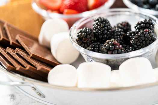 Making s'mores on a homemade star-shaped chocolate graham cracker with toasted marshmallow and fruits.