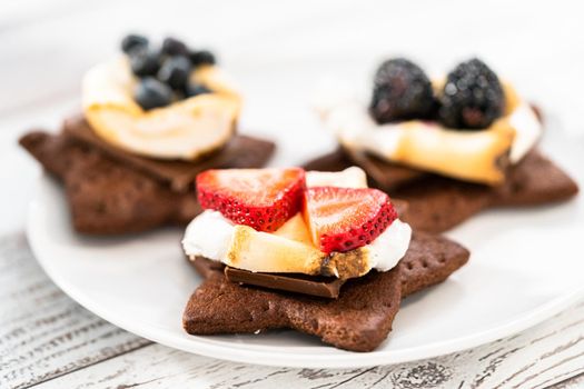 Making s'mores on a homemade star-shaped chocolate graham cracker with toasted marshmallow and fruits.