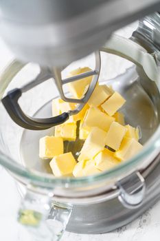 Whisking buttercream frosting in a glass mixing bowl with an electric kitchen mixer for American flag mini cupcakes.