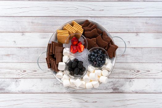 Arranging fruit s'mores charcuterie board on a white tray.