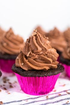 Piping chocolate ganache frosting on top of chocolate cupcakes.