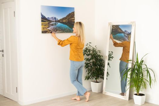 Woman hanging a photo canvas on a wall