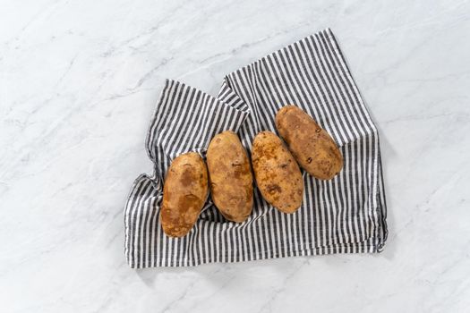 Flat lay. Pressure Cooker Baked Potatoes. Drying washed raw potatoes with a kitchen towel.