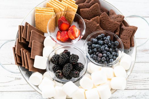 Arranging fruit s'mores charcuterie board on a white tray.