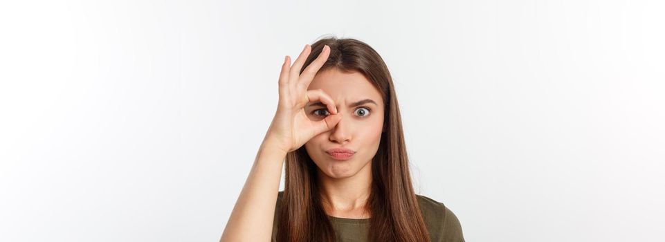 Close up portrait of cheerful, cute, stylish,attractive, trendy girl making binoculars with fingers, isolated on grey background, having good mood.