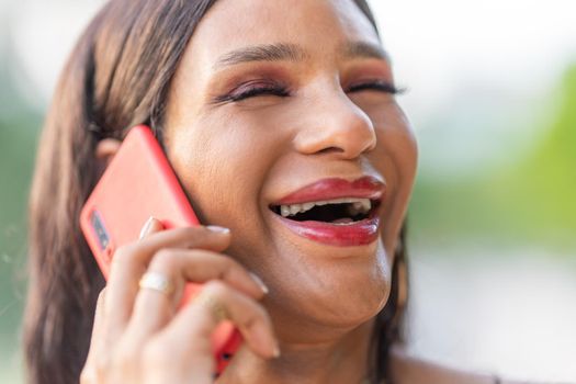 Close up portrait of a latina Transgender woman laughing while talking to the mobile outdoors