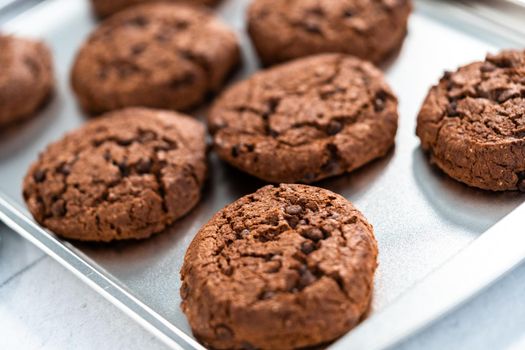 Freshly baked double chocolate chip cookies on a baking sheet.