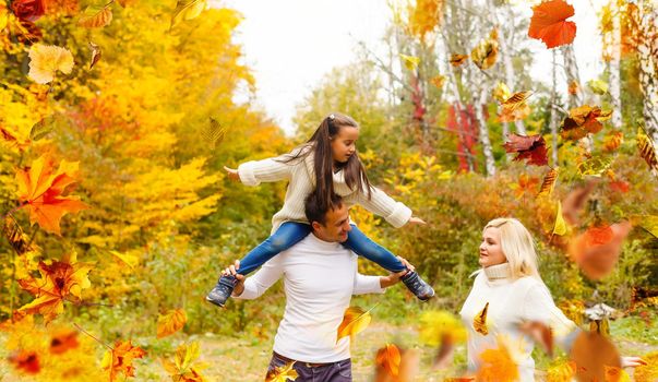 family walking in an autumn park with fallen fall leaves. High quality photo