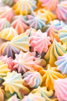Multicolored unicorn meringue cookies on a white serving plate.