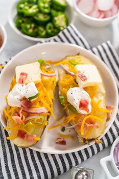 Pressure Cooker Baked Potatoes. Garnished large baked potatoes with butter, sour cream, cheese, and bacon bits on a white plate.