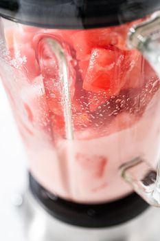 Blending ingredients in a kitchen blender to prepare frozen watermelon margarita.