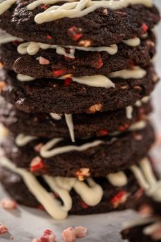 Freshly baked chocolate cookies with peppermint chips with a white chocolate drizzle on top.