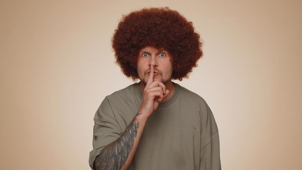 Shh be quiet please. Portrait of bearded adult man 30 years old presses index finger to lips makes silence gesture sign do not tells secret. Young adult handsome guy posing on beige studio background