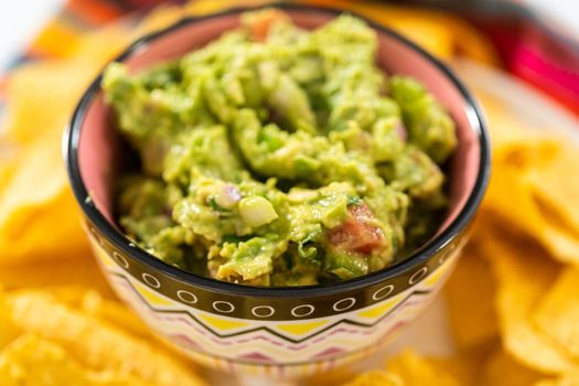 Classic guacamole dip in a small bowl with corn tortilla chips.