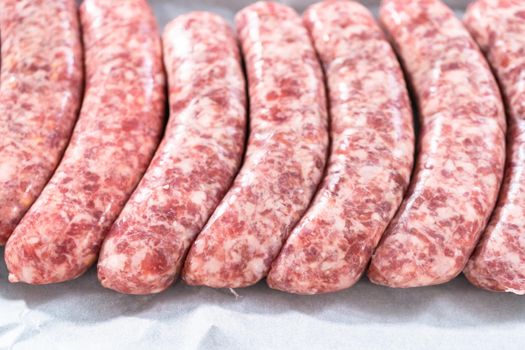 Raw beer bratwursts in the row on a small tray.