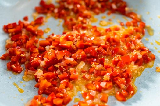 Frying onion and red bell pepper in olive oil on a nonstick frying pan to bake turkey empanadas.