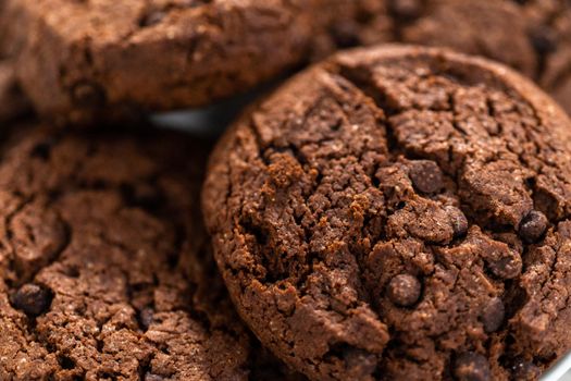 Freshly baked double chocolate chip cookies on a white plate.