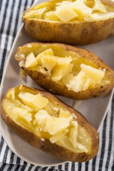 Pressure Cooker Baked Potatoes. Sliced cooked whole potatoes on a white plate to make baked potatoes.