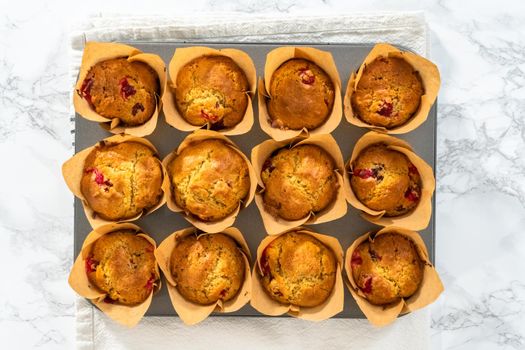 Flat lay. Freshly baked cranberry muffins in brown paper muffin cups.