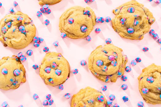 Freshly baked unicorn chocolate chip cookies with rainbow chocolate chips on the counter.