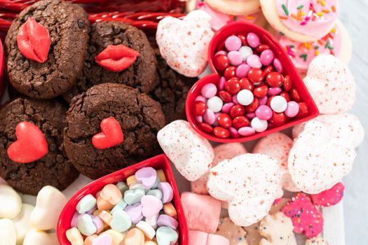 Valentines Day cheese board with a variety of cookies and candies.