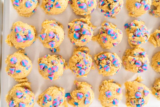 Chilled cookie dough scoops on the baking sheet to bake unicorn chocolate chip cookies.