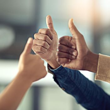 Keep up the exceptional work. Closeup shot of a group of businesspeople giving thumbs up together