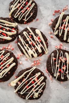 Freshly baked chocolate cookies with peppermint chips with a white chocolate drizzle on top.