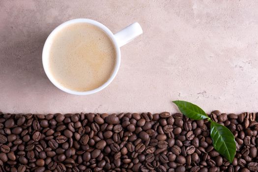 Top view with place for text roasted coffee beans border and cup of coffee on a light brown background.