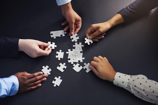 Were all part of the puzzle of life. a group of businesspeople fitting puzzle pieces together