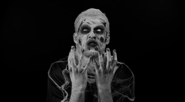 Dissatisfied frightening man with Halloween zombie bloody wounded makeup asking reason of failure, expressing disbelief irritation, feeling bored, disappointed in result, bad news. Sinister undead guy