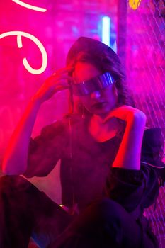Caucasian woman in sunglasses posing in fog in neon studio