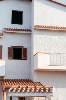 Typical white house facade part in italian city near the sea. Brown windows on white wall. Mediterranean village style architecture.