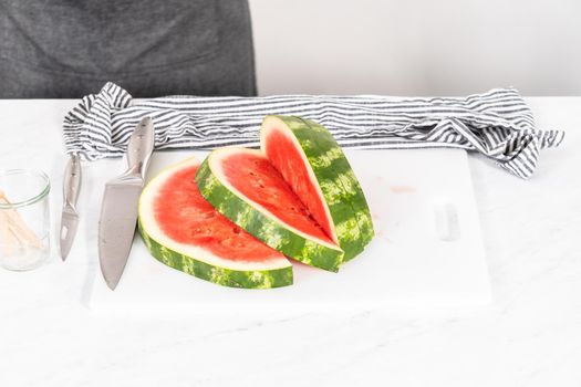 Slicing riped red watermelon to prepare chili lime watermelon pops.