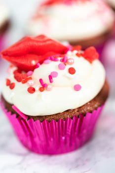 Red velvet cupcakes with cream cheese frosting and decorates with heart and kiss shaped red chocolates.