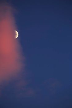 Crescent moon between pink clouds on blue sky in southern Spain in summer