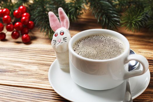 Christmas morning 2023 in traditional Christmas colors. Christmas toys, coffee and the symbol of 2023 - a rabbit on a wooden table. copy space