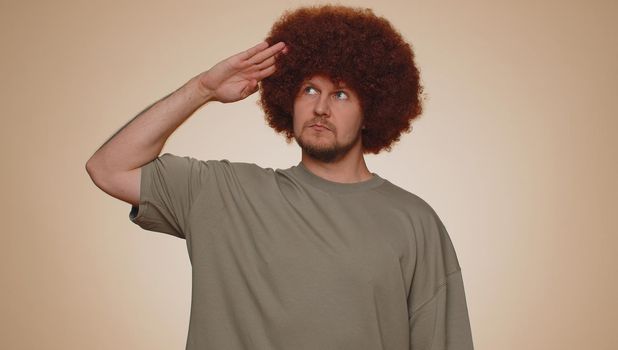 Yes sir. Subordinate, responsible, serious bearded man giving salute listening to order as if soldier, following discipline, obeying, expressing confidence. Young guy boy on beige studio background