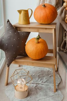 Autumn interior in a photo studio, with pumpkins, a vase and a wooden stool.