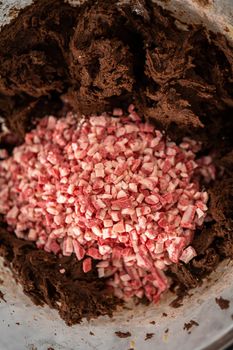 Folding in peppermint chocolate chips into a chocolate cookie dough to bake chocolate cookies with peppermint chips.