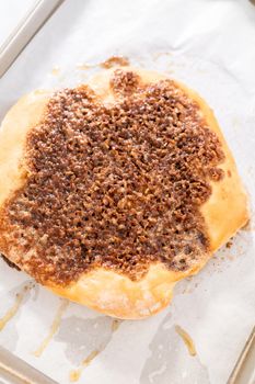 Preparing cinnamon dessert pizza on a baking sheet lined with parchment paper.