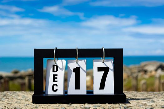 Dec 17 calendar date text on wooden frame with blurred background of ocean. Calendar date concept.