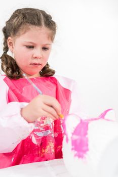 Little girl painting Halloween pumpkin with acrylic paint.