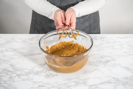 Mixing ingredients in a large glass mixing bowl to bake gingerbread cupcakes.